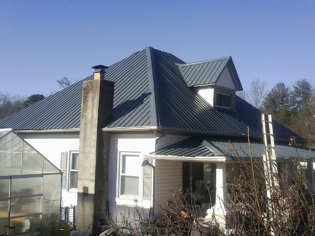 Dark blue standing seam metal roof on a white farmhouse with dormer — Slate & Tile Roof Repair by Roofing Brothers in Lake Zurich