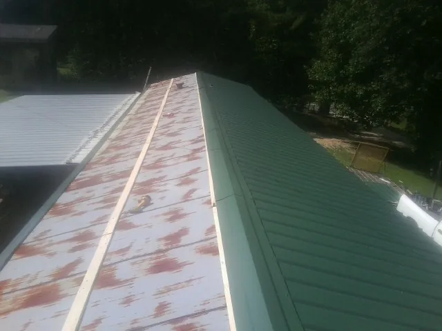 Old rusted panels beside newly installed green metal roofing — Wind Damage Roof Repair by Roofing Brothers in Lake Zurich