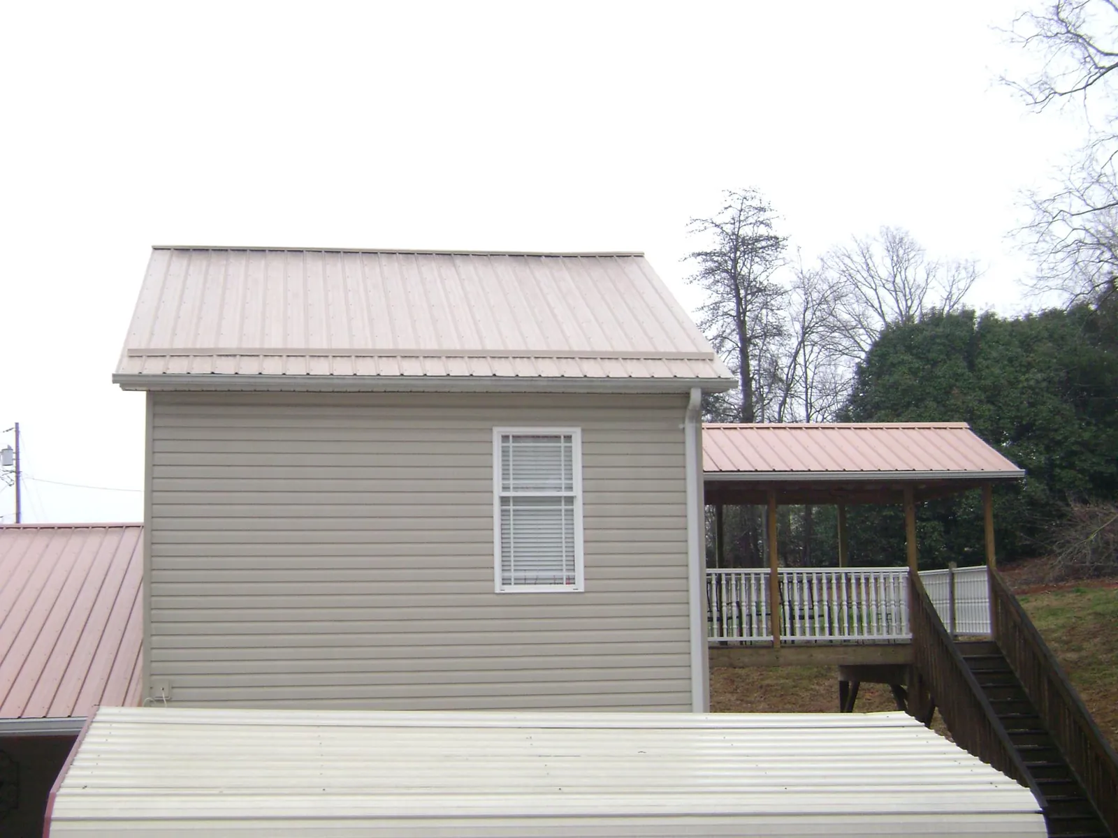 Tan metal roofs on a two story addition and attached porch, from a Roof Replacement job in Lake Zurich