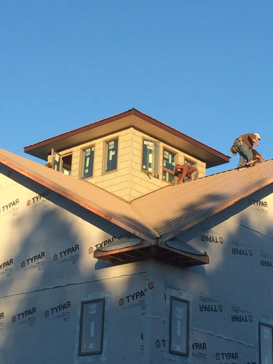 Roofers working around a rooftop cupola on a new metal roof at sunset — Roof Waterproofing in Lake Zurich by Roofing Brothers